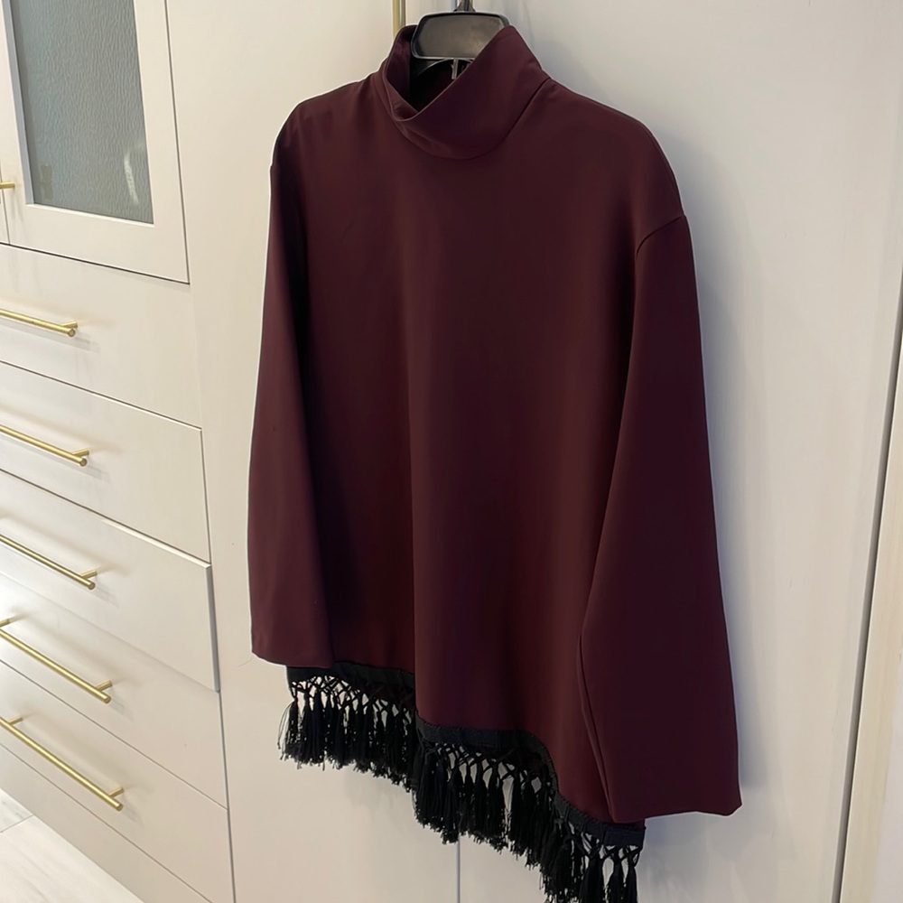Woman’s tunic top with mock turtle neck and black fringes around the bottom